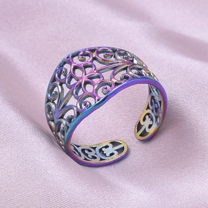 Détail d'une bague arc-en-ciel en acier inoxydable ajouré avec fleurs sur soie