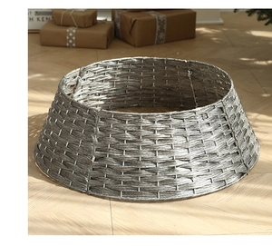 Detail of grey hand-woven Christmas tree skirt on wooden floor with festive gift boxes