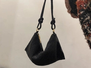 Detail of hand-woven black beaded hobo bag with knotted strap and gold-tone zipper