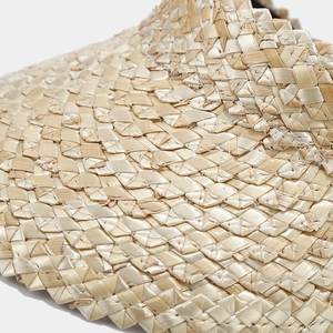 Macro shot of natural wheat straw sun hat showing detailed woven texture and craftsmanship