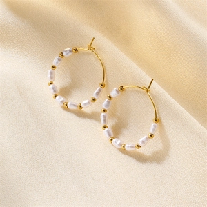 Macro shot of circular freshwater pearl earrings with gold beads on champagne velvet