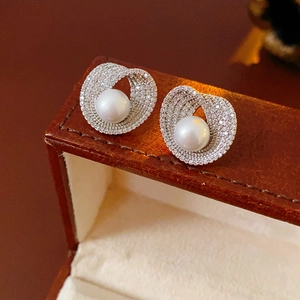 Vue macro de boucles d'oreilles perles blanches avec monture argentée sertie de zircons