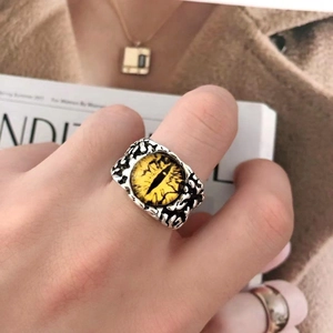 Macro detail of silver-toned punk eye ring with yellow cat-eye stone on a model hand