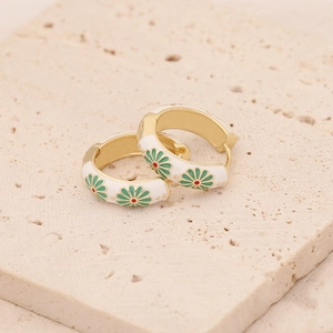 Vue détaillée des boucles d'oreilles dorées à motif marguerite verte et émail blanc