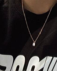 Close-up of a 18k gold plated necklace featuring a rectangular emerald green zircon pendant