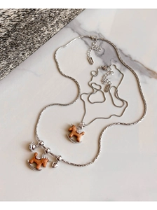 Détail du collier avec pendentif cheval de bois, accents d'étoiles argentées et de clochettes