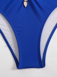Close-up of royal blue bikini bottom with a detailed golden heart-shaped metal pendant