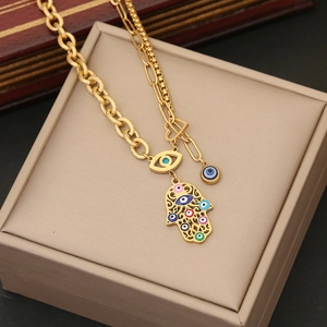 Macro detail of gold layered necklace with Fatima hand and evil eye enamel pendants