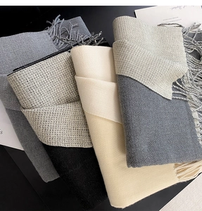 Stacked collection of luxury thick cashmere-feel scarves with fringe details in neutral tones
