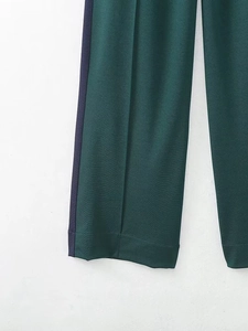 Détail du pantalon vert foncé avec bandes latérales bleu marine et texture de sergé