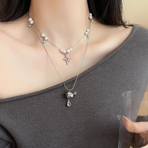 Detail of layered pearl necklace with star and Saturn pendant on a female model