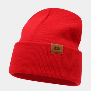 Detail of red knit beanie with brown leather MOM patch and ribbed texture design