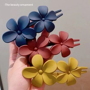 Close-up of matte flower hair clips in navy, red and yellow showing high-quality texture