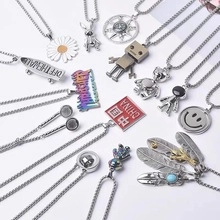 Flat lay of diverse titanium steel necklaces featuring daisy, astronaut and robot pendants