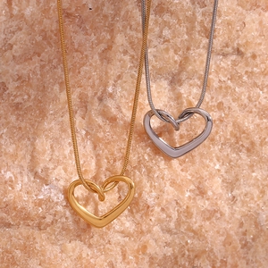 Detail of gold and silver heart pendants on fine snake chains over natural stone background