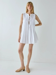 Détail de la mini-robe plissée blanche sans manches avec liens et plis accordéon
