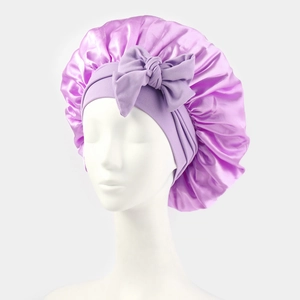 Purple satin sleep bonnet for women featuring a large decorative bow and elastic band