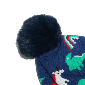 Detailed macro shot of blue knitted kid hat with fluffy pompom and dinosaur patterns