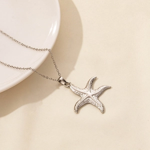 Detail of silver starfish pendant necklace with realistic textured surface on ceramic dish