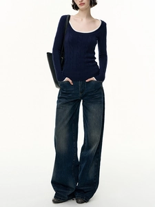 Detail of navy cable-knit sweater with white contrast collar and dark wash wide jeans