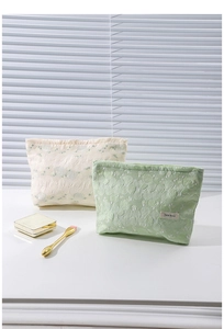 Close-up of textured floral fabric makeup bags in mint green and creamy white colors