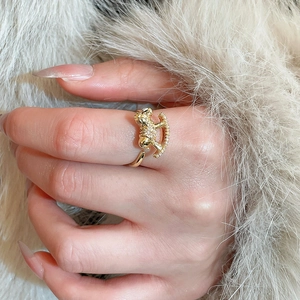 Detail of a gold rocking horse ring with zircon pavé on a soft beige fur background