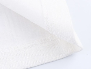 Macro shot of white imitation linen fabric showing fine mesh texture and hem stitching