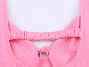 Detailed macro view of pink linen dress featuring elastic smocking and tie-bow detail