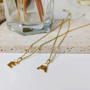Macro shot of gold necklaces with letter E and A pendants featuring radial textures