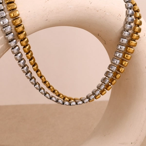 Detail of square bead geometric necklaces in gold and silver finish on ceramic