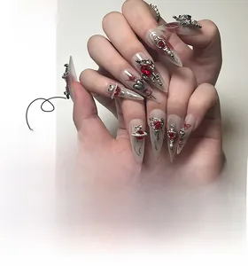 Détails de faux ongles stiletto avec effet marbré rouge et breloques gothiques argentées