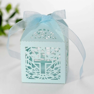 Detail of light blue laser-cut candy box featuring a cross pattern and matching ribbon bow