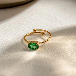 Detail view of 18k gold adjustable ring featuring a green oval zircon stone and ball accents