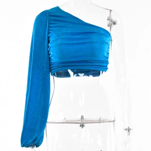 Détail du crop top bleu à une épaule avec texture froncée et manche longue