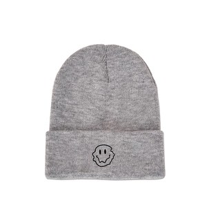 Detailed view of dark grey knitted beanie with embroidered twisted smiley face design