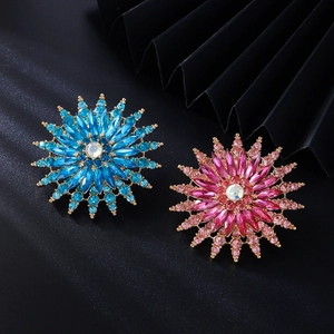 Macro shot of flower-shaped brooches with blue and pink crystals on black silk