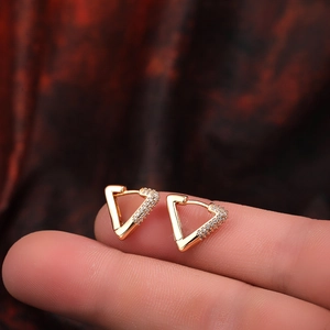 Close-up of heart-shaped 18K gold earrings with micro-inlaid zircons held on a finger