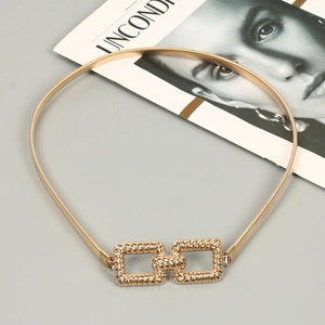 Detail of gold elastic metal waist chain featuring embossed rectangular interlaced buckle