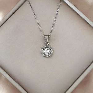 Macro shot of silver halo pendant necklace with zircon stone on silk fabric