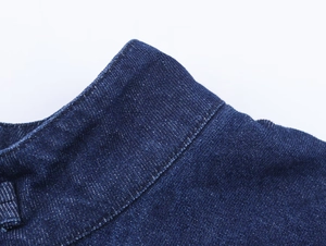 Close-up of the denim knot collar detail and stitching on this stylish dark blue cape top