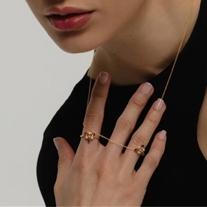 Model wearing gold jewelry set featuring orange pear-cut gemstone butterfly necklace and ring