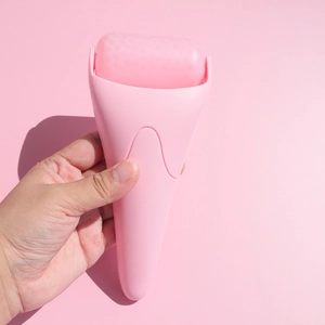 Close-up of pink face ice roller being held for soothing facial skin massage treatment