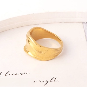 Detailed view of an irregular wavy gold ring with minimalist textured surface on a white setup