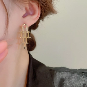 Detail shot of long gold geometric drop earrings featuring a metallic tiered modular design