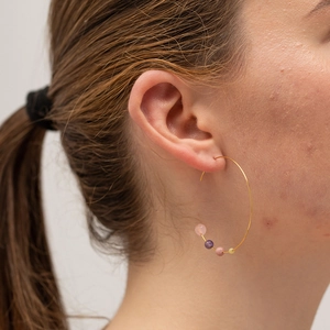 Golden C-shaped stainless steel hoop earrings with colorful beads on a female model