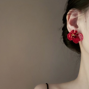 Detail view of red velvet flower earrings with gold center on model's ear
