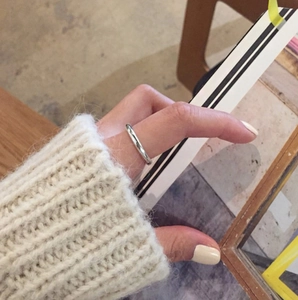 Detail of minimalist S925 sterling silver thin ring worn on finger with a polished finish
