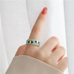 Close-up of wide mint green enamel ring with evil eye pattern and gold eyelash details