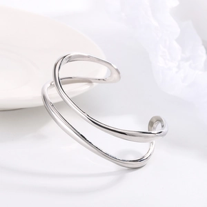 Primer plano de un brazalete abierto plateado Mobius de doble capa y diseño geométrico