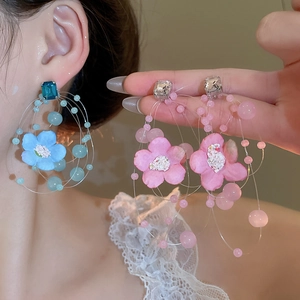 Detail of floral beaded hoop earrings with light blue fabric flowers and rhinestones